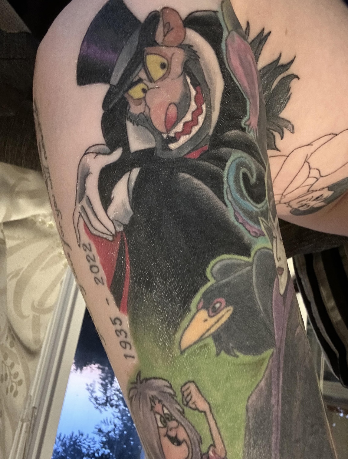 Colour comic character sleeve tattoo with memorial dates, upper arm